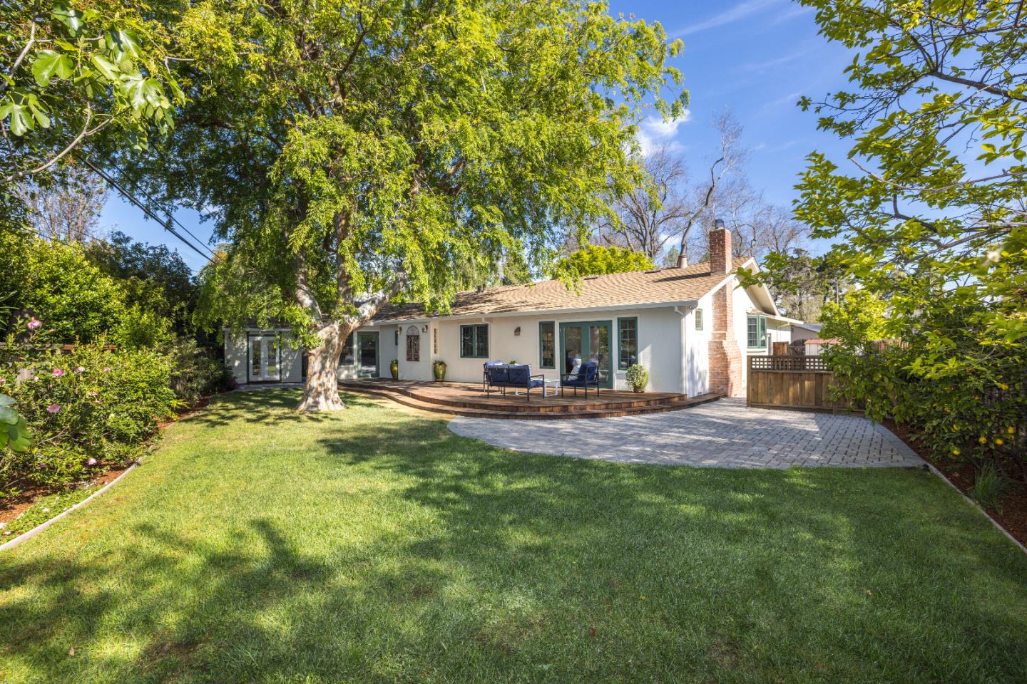 Palo Alto backyard with healthy lawn, mature trees, and brick patio